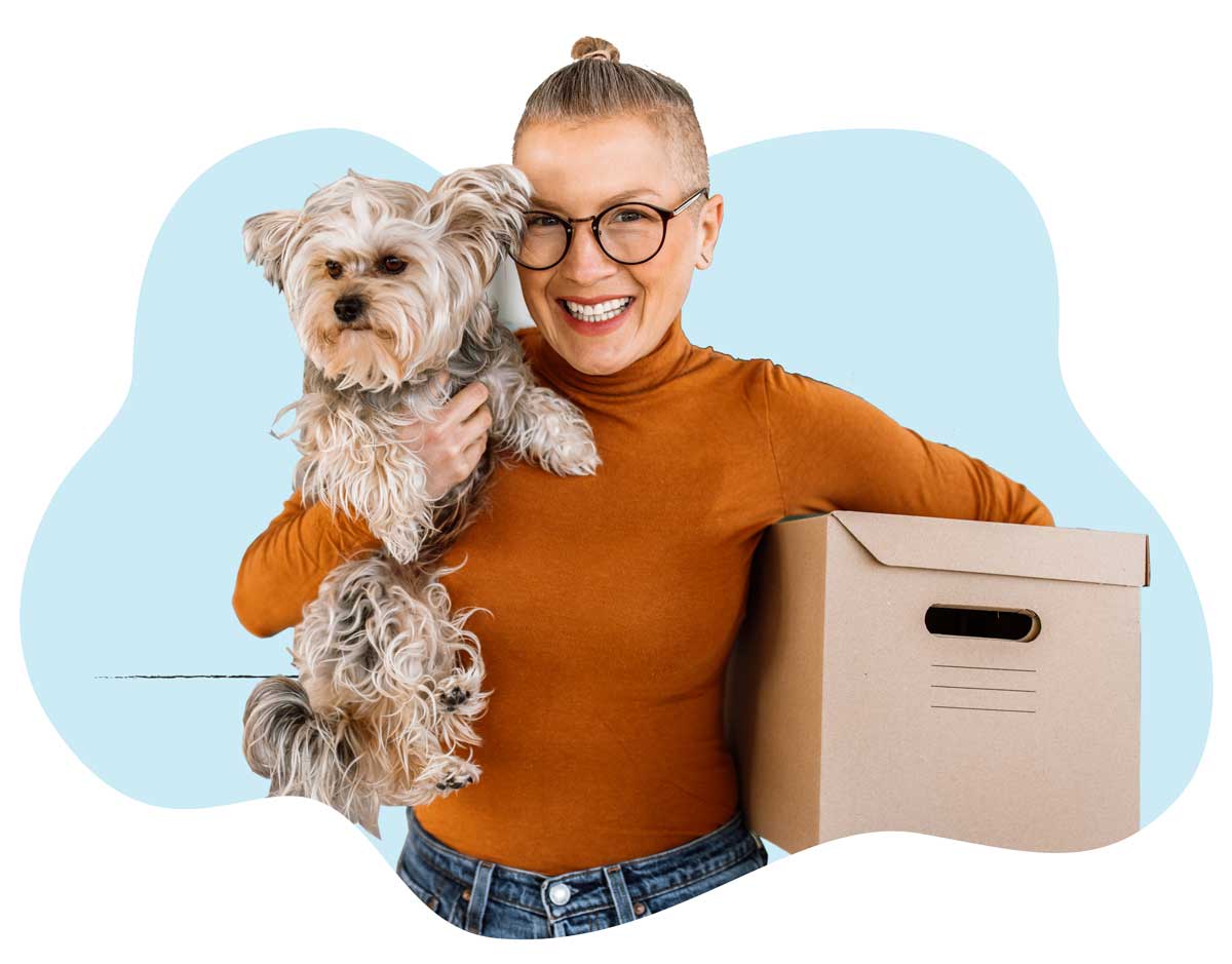 A woman in an orange sweater holding her small brown dog