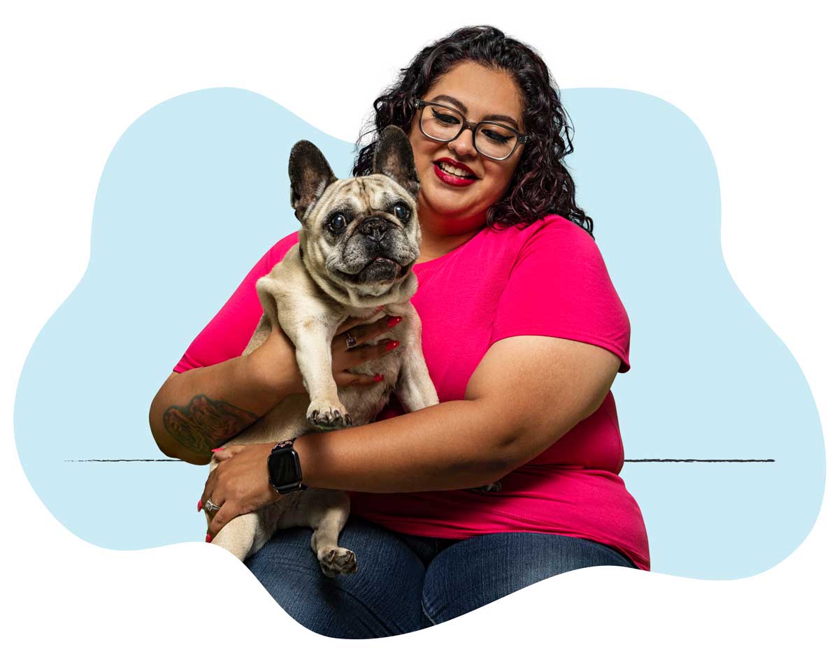 A woman in a neon pink shirt holding her French Bulldog