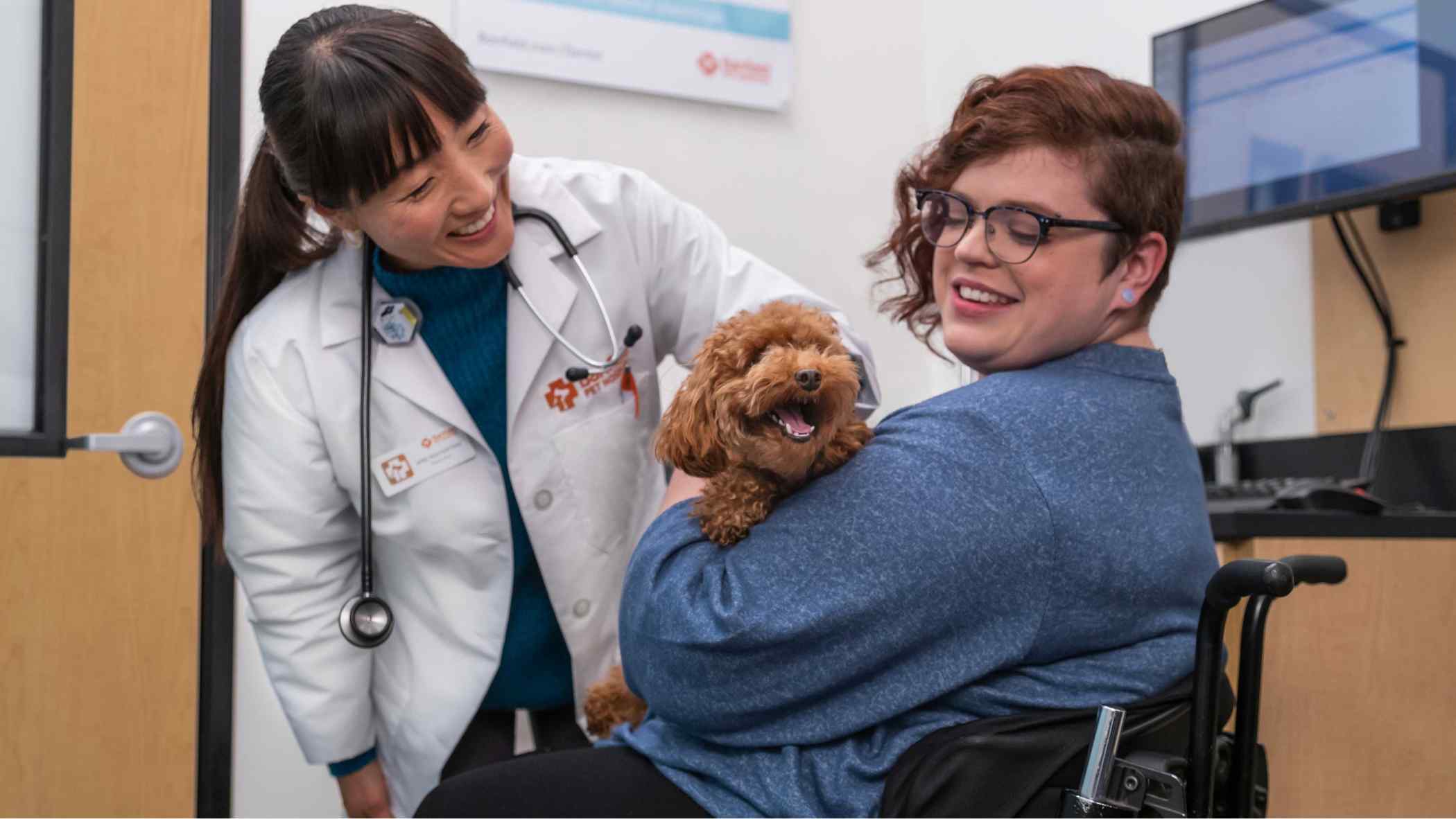 A woman in a wheelchair holding her Goldendoodle puppy
