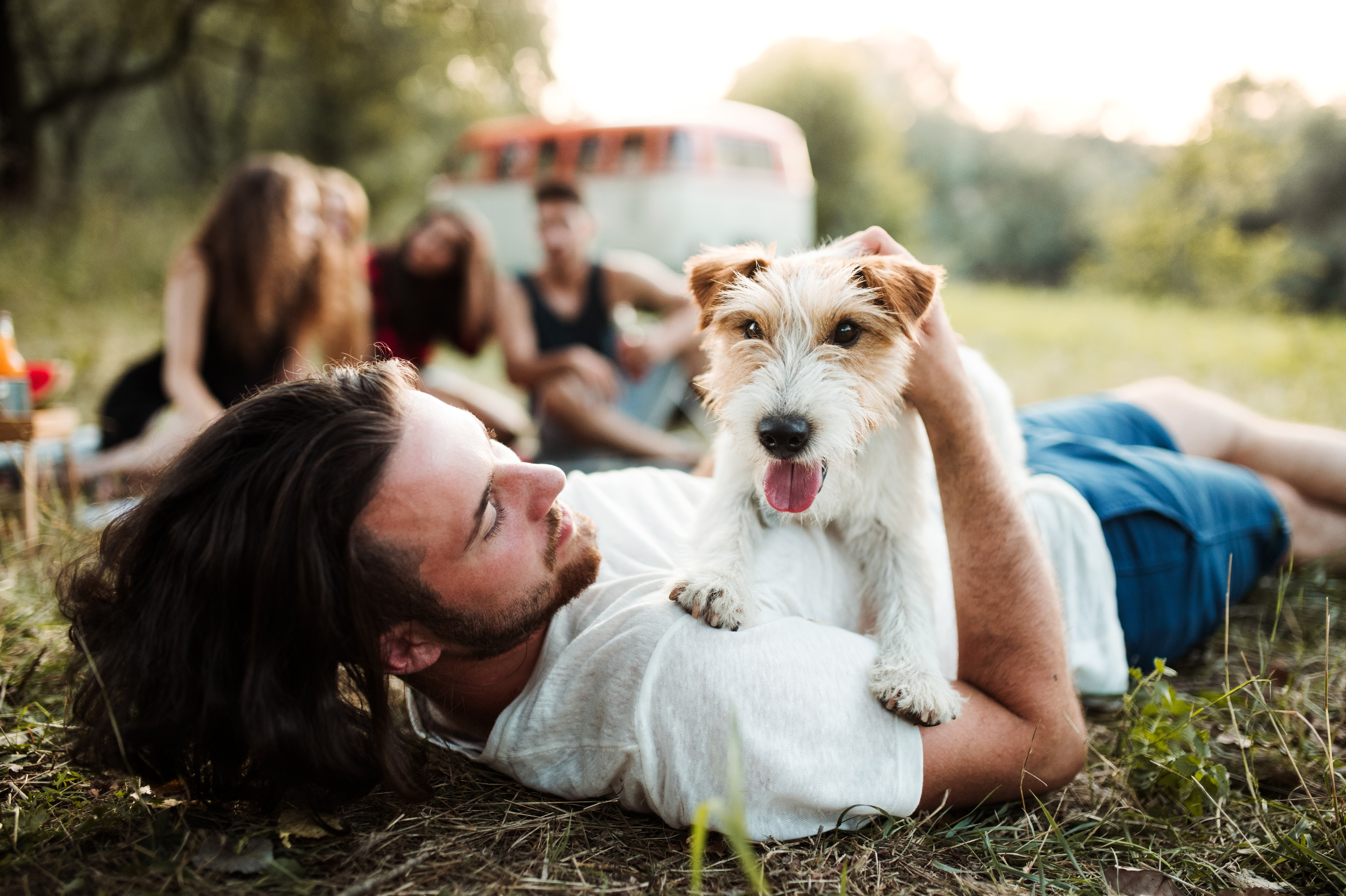 A man lays on grass with his small dog lying on his chest