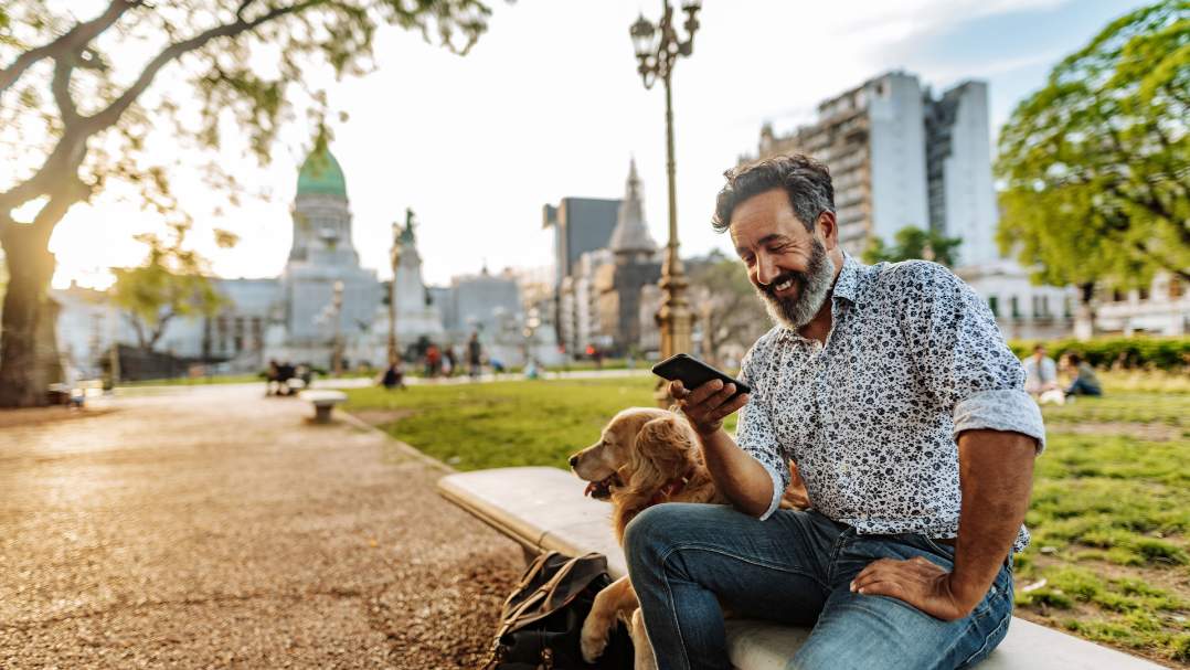 Person sitting outside with dog using phone